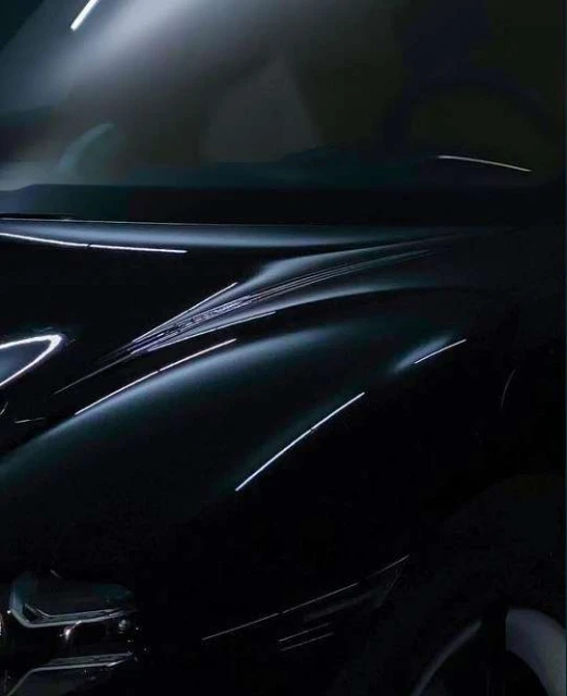 Close-up of a sleek, dark-colored car hood featuring sharp lines and dramatic lighting that accentuates its modern design and curvature.