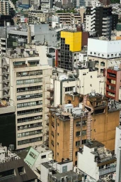 High-angle aerial view of dense urban buildings featuring varied rooftops, concrete structures, and architectural details.