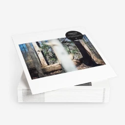 A stack of white art books or photography monographs photographed against a clean white seamless studio background.