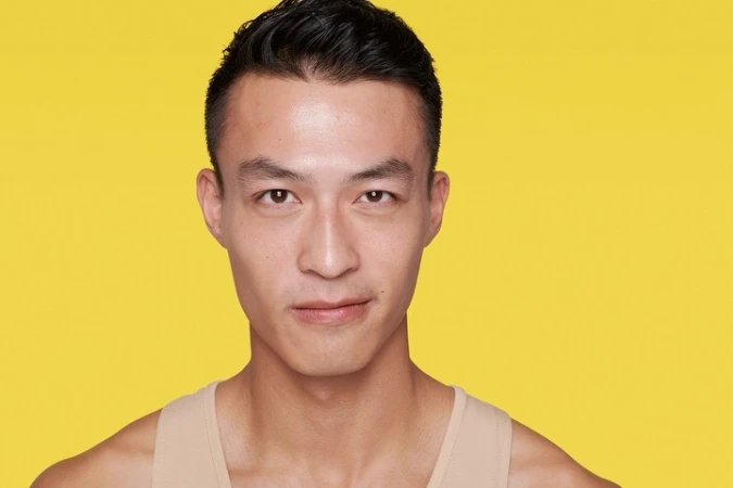 Portrait of adult Asian man with black hair against a yellow background. Head and shoulders shot, looking directly at the camera.