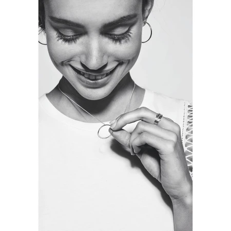 Close-up portrait of a smiling woman wearing hoop earrings, rings, and a delicate pendant necklace by photographer Terry Doyle.