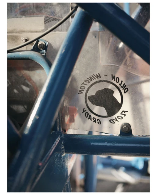 Close-up of a blue metal frame structure with a clear decal featuring a dog illustration and reversed text.