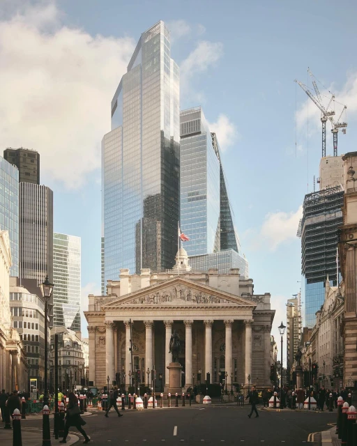 Cityscape featuring modern glass skyscrapers in London, UK, with the Royal Exchange building in the foreground and pedestrians crossing the street.