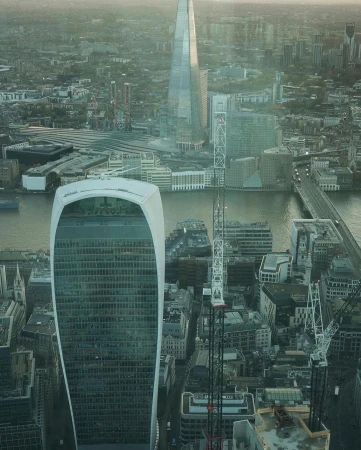 View of London skyscrapers, including The Shard and the Walkie Talkie building, with the River Thames flowing through the city.