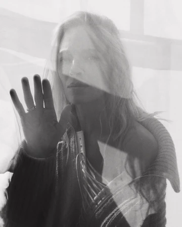 Monochrome portrait of a woman pressing her hand against a translucent layered surface by Tess Ayano.