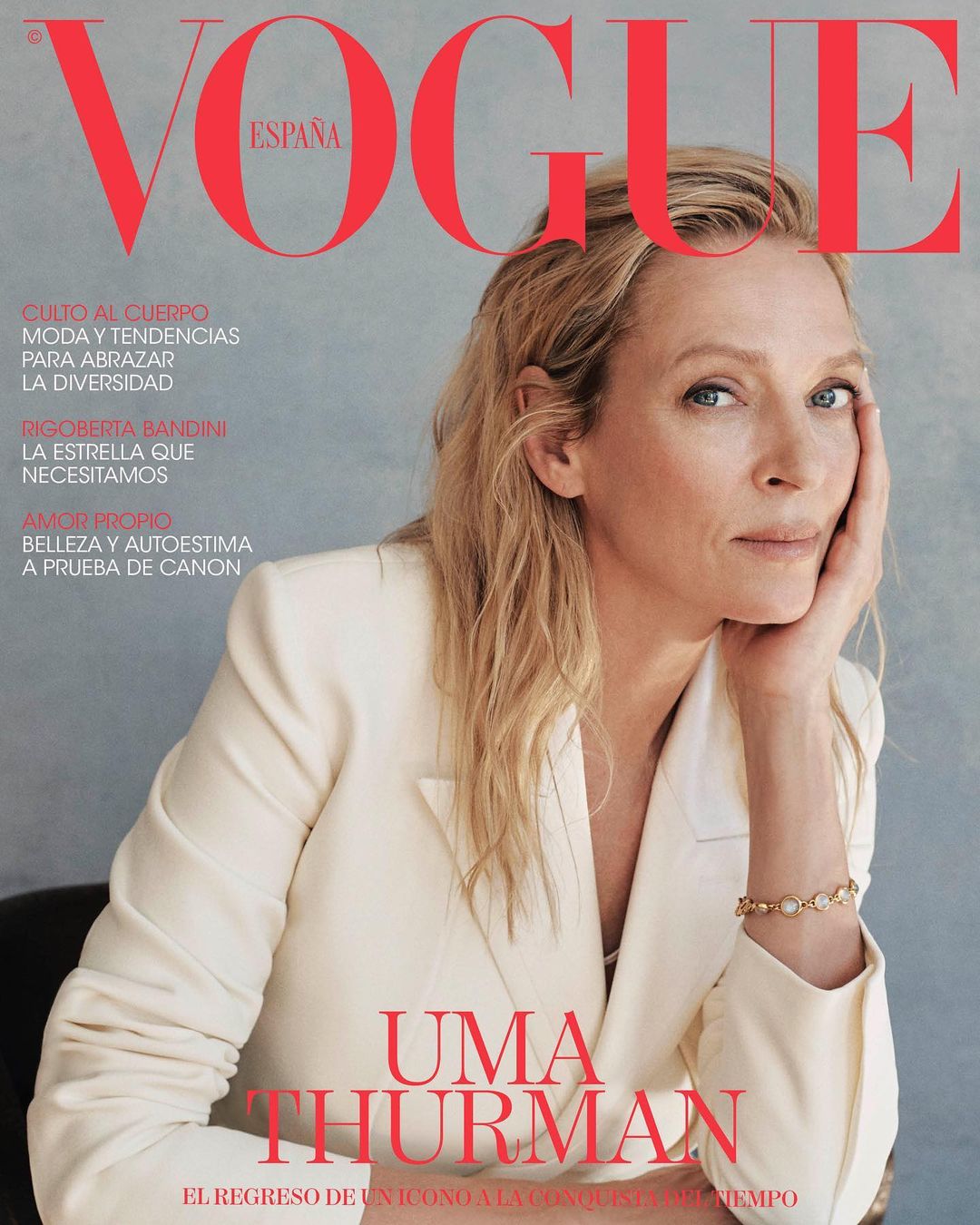 Vogue España cover featuring Uma Thurman in a white suit, portrait of a blonde woman on a magazine cover with text, posing indoors.