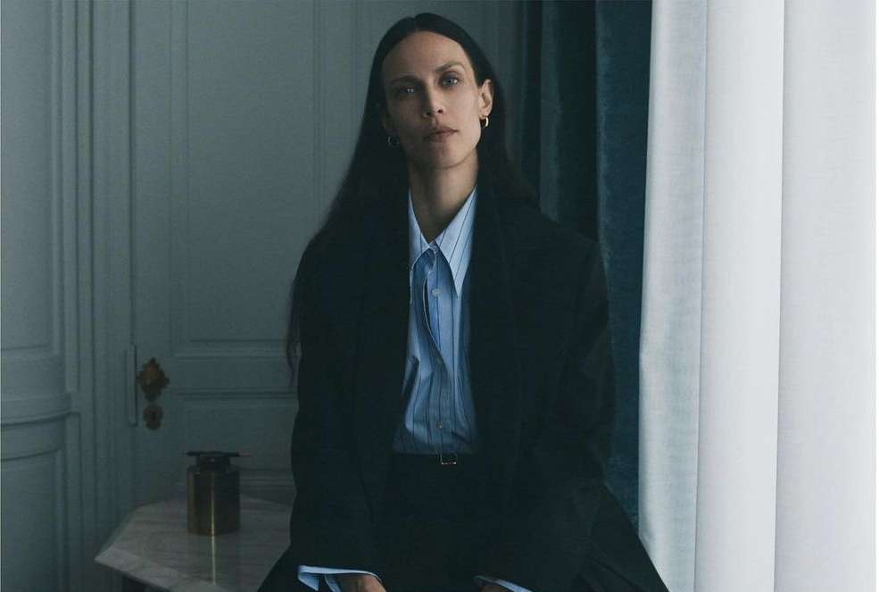 Portrait of a woman with long dark hair wearing a pinstripe button-down shirt and a dark blazer by photographer Tess Ayano