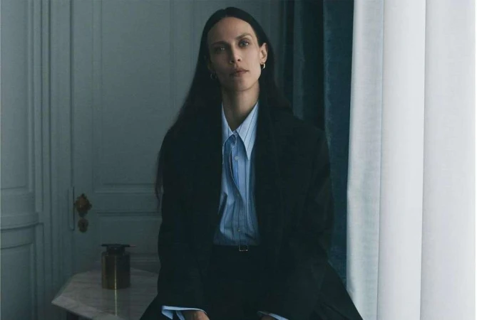 Portrait of a woman with long dark hair wearing a pinstripe button-down shirt and a dark blazer by photographer Tess Ayano