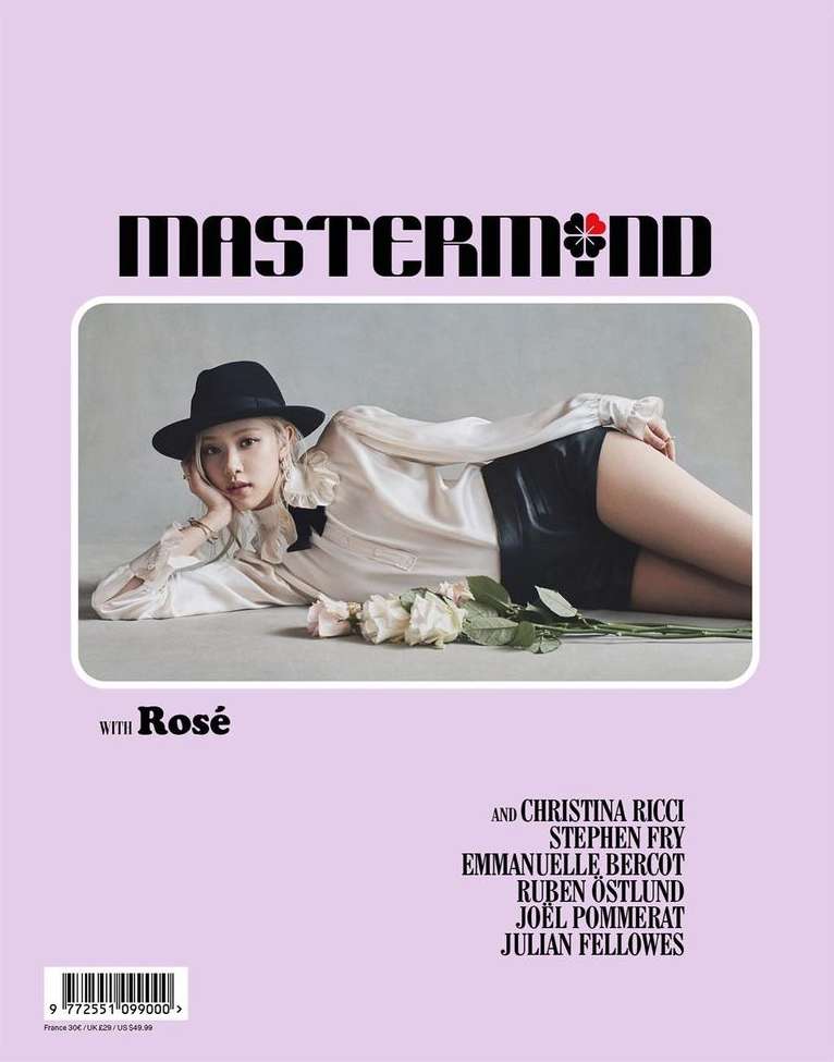 Magazine cover featuring a model in black hat and shorts, white blouse, reclining near white roses against a lilac background.