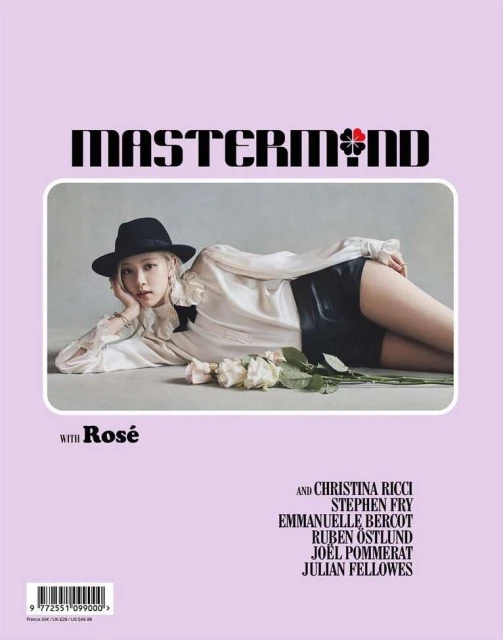 Magazine cover featuring a model in black hat and shorts, white blouse, reclining near white roses against a lilac background.