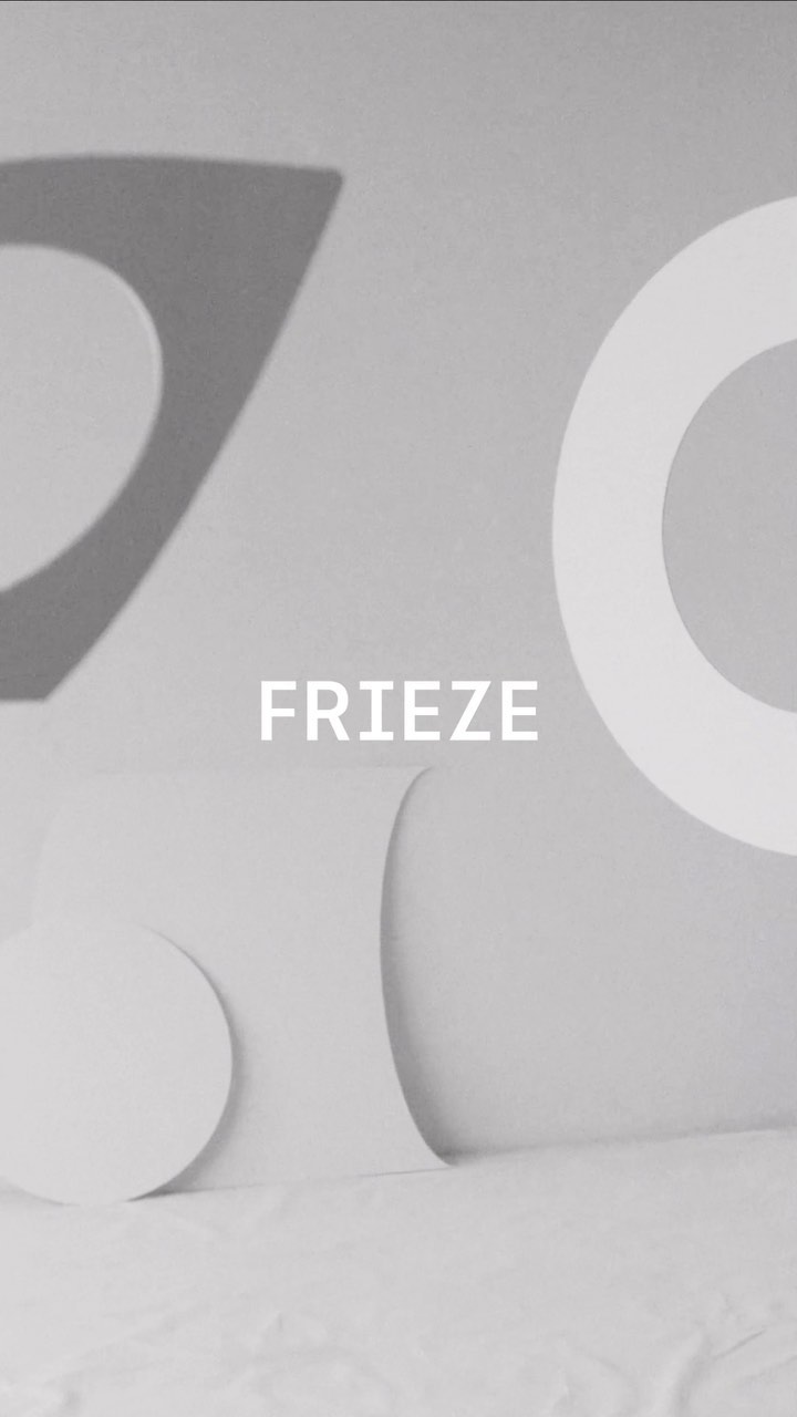 Abstract monochromatic image with white geometric shapes against a light gray background, including the word FRIEZE in the center.
