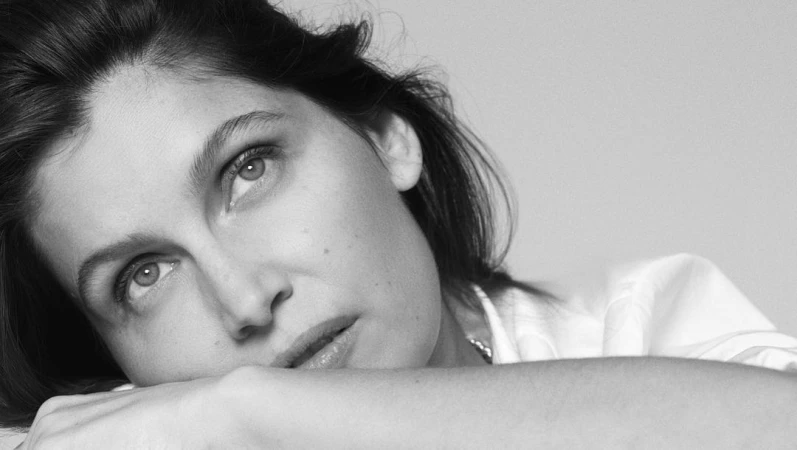 Close-up portrait of a woman resting her chin on her crossed arms, looking upward in a monochrome photograph.