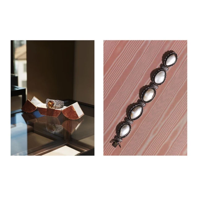 A ring with an amber-colored gemstone in a display case, and a mother-of-pearl bracelet on a pink wood background.