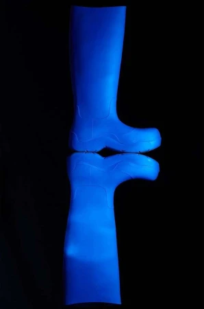 A bright blue rubber boot is isolated on a black reflective surface in a product-style shot showing the design and texture of the material.