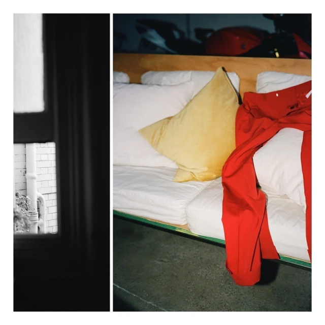 Interior shot featuring a cushioned daybed with white bedding and a yellow pillow, contrasted with a window view of a gray brick wall.