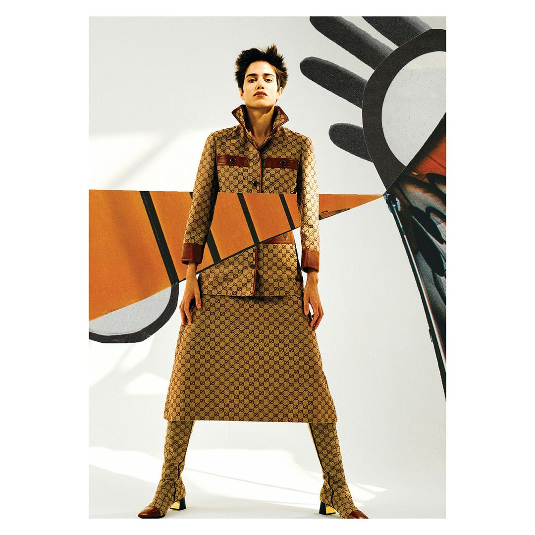 A female fashion model poses indoors wearing a Gucci patterned jacket, skirt, and boots, complemented by abstract graphic elements in the background.