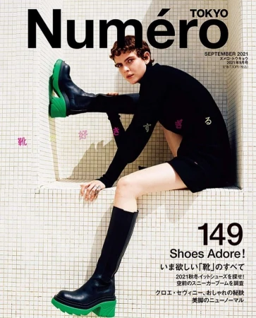 Magazine cover featuring a female model in black attire and chunky green-soled boots posed in a tiled niche.