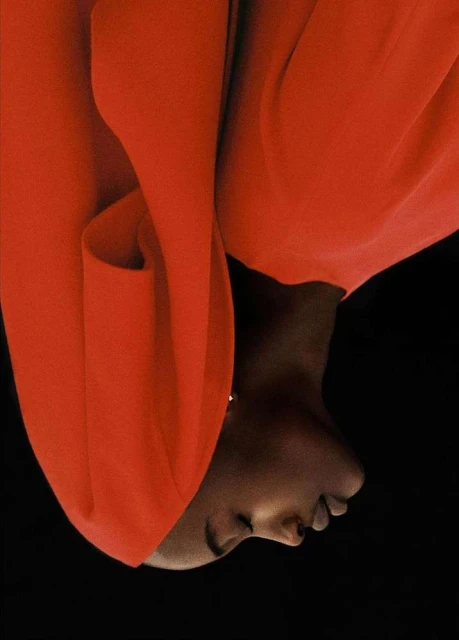 Fashion shot of a Black woman in red attire against a black background, emphasizing her skin tone and the vibrant colour contrast.