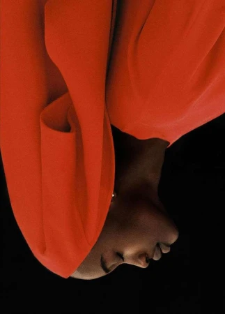 Fashion shot of a Black woman in red attire against a black background, emphasizing her skin tone and the vibrant colour contrast.
