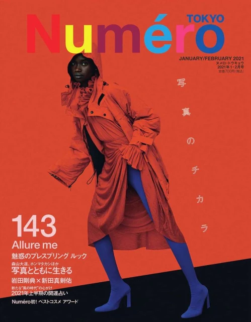 Magazine cover featuring a Black female model in an orange hooded dress with blue leggings and heeled booties against an orange background.