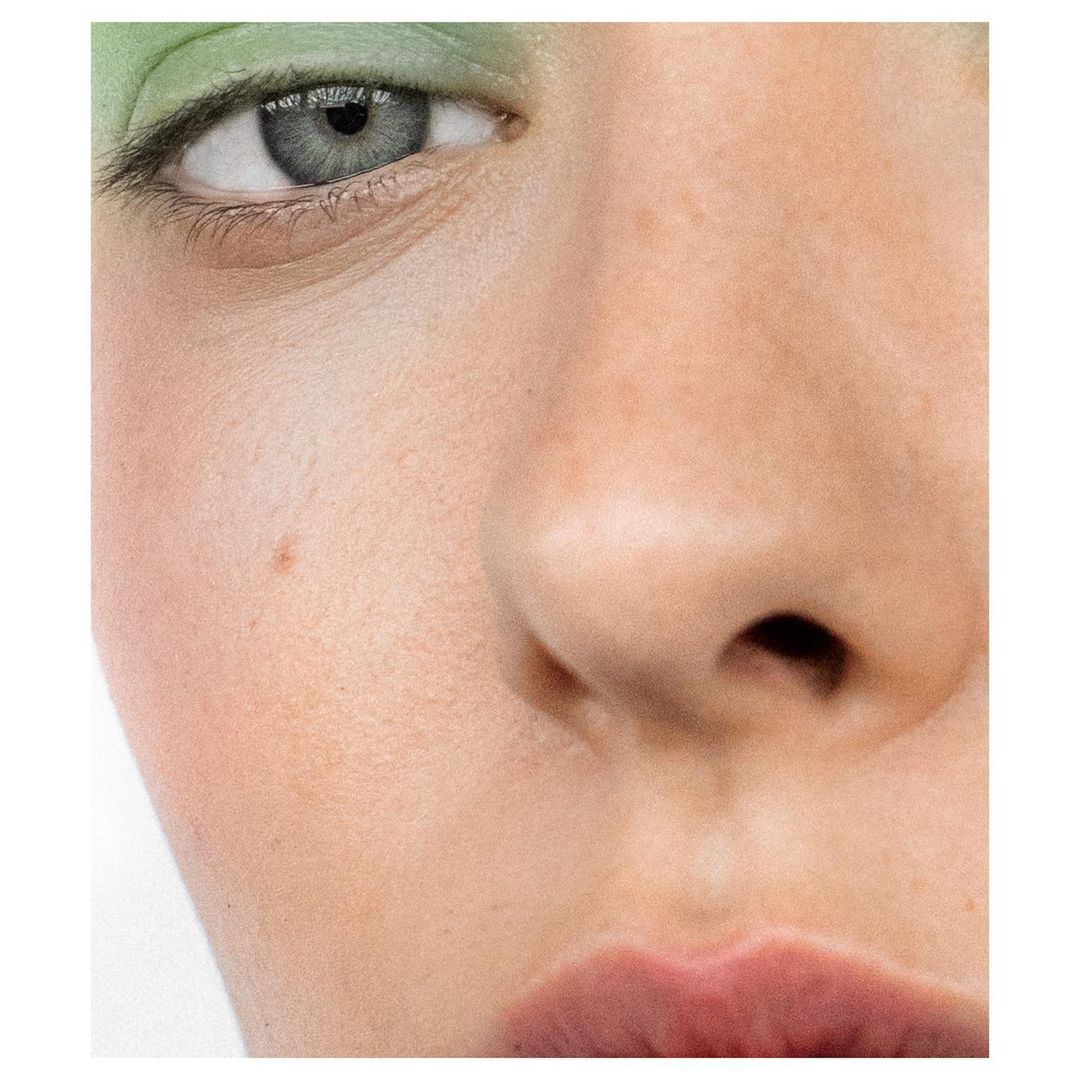 Macro close-up of a person's face, showcasing eye makeup. The focus highlights the texture of the skin and delicate facial features.