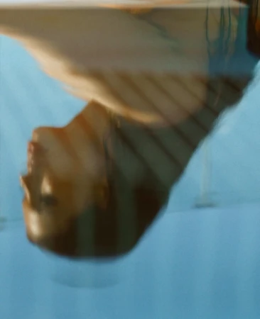 Abstract portrait of an adult female, shot from a low angle, featuring soft lighting and a blue background, blurred for a dreamlike effect.