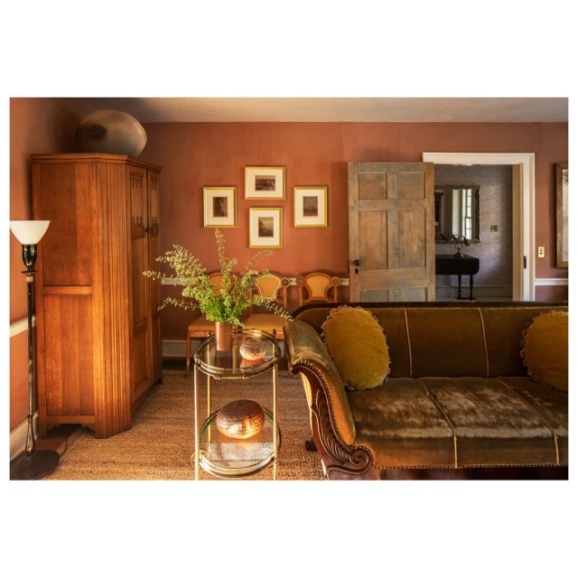 Interior of a living room with a brown couch, wooden cabinet, decorative vase, lamp, and artwork creating a warm and inviting atmosphere.