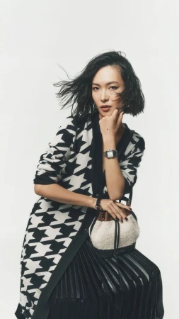 Asian woman with dark short hair wearing a black and white houndstooth cardigan against a plain white background