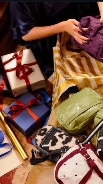 A person is packing a variety of handbags and gift-wrapped boxes with ribbons into a yellow and white striped box, creating a vibrant scene.