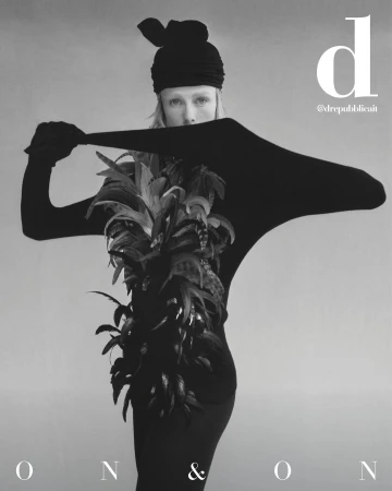 Monochrome fashion shot features a model in a black outfit and feathered garment against a neutral backdrop, highlighting editorial style.