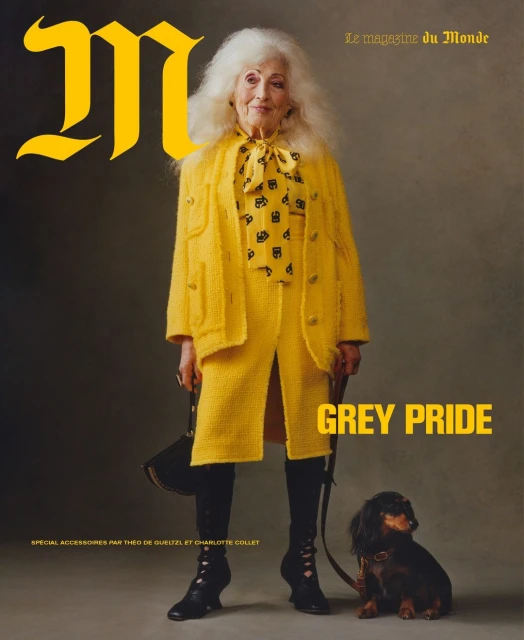 Elderly woman poses in yellow tweed suit with her dog for magazine cover; she stands against a neutral backdrop. Fashion editorial shot.