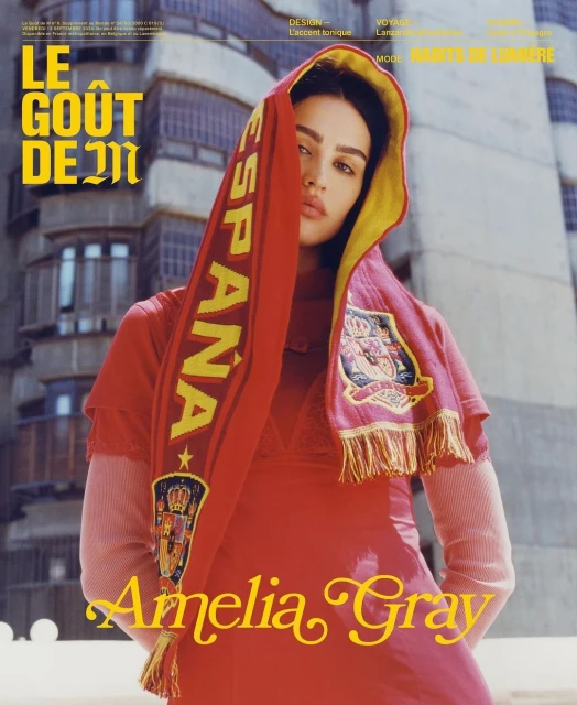 Fashion editorial shot of woman in red dress and Spain scarf against urban background. Model Amelia Gray poses outdoors.