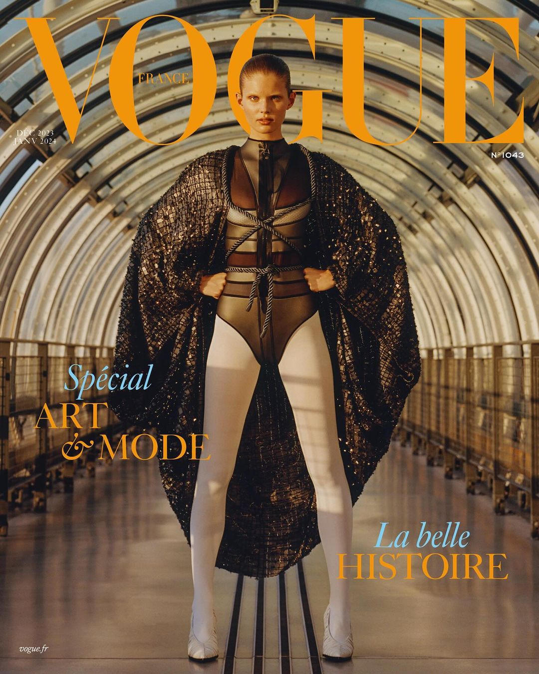 Vogue France cover featuring a fashion model in a bodysuit, cape, and white tights, posing in a tunnel-like setting.