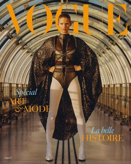 Vogue France cover featuring a fashion model in a bodysuit, cape, and white tights, posing in a tunnel-like setting.