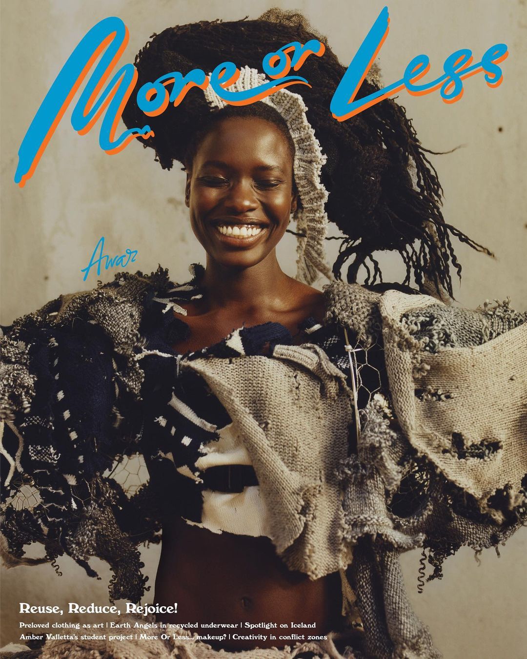 Magazine cover featuring smiling Black woman in avant-garde dress of ragged textiles, set against a neutral background, text visible.