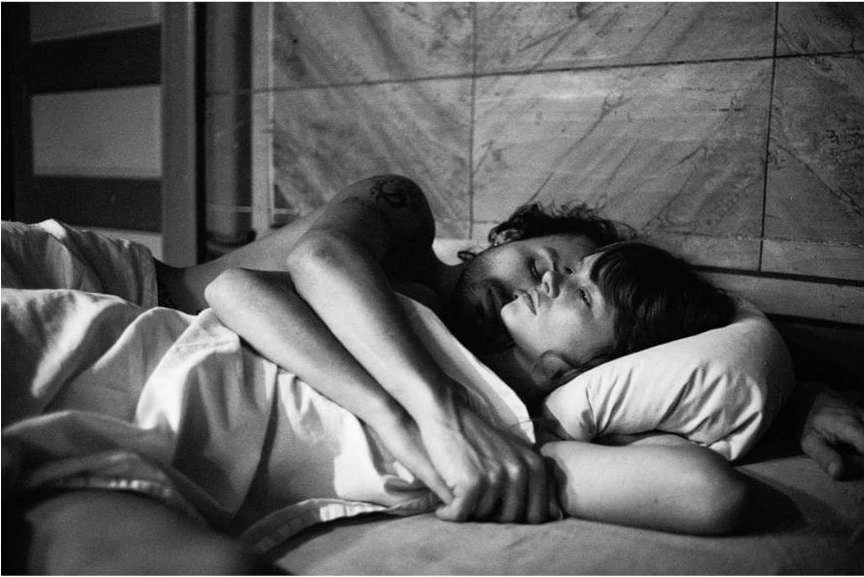 Monochrome image capturing an intimate moment of a man and woman sleeping in bed, showcasing a close-up shot emphasizing their closeness.