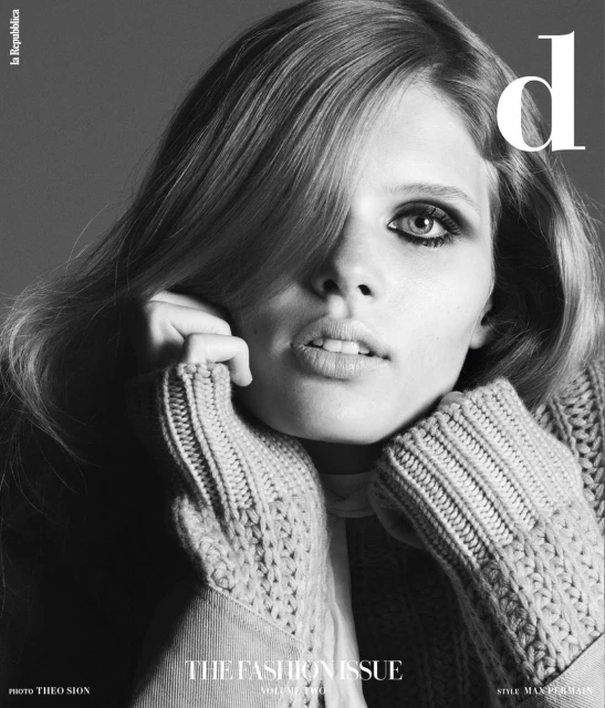 Black and white fashion magazine cover featuring a woman with long wavy hair and a chunky knit sweater, posing in a close-up shot.