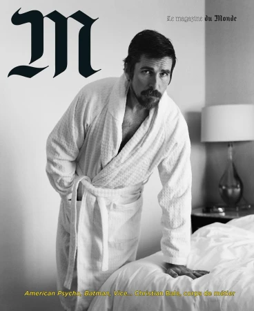 Magazine cover featuring Christian Bale in a white bathrobe leaning on a bed in a neutral-toned interior with magazine text.