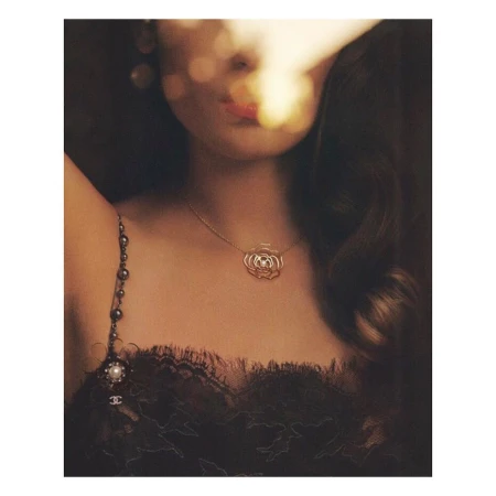 Close-up portrait of a woman wearing a gold flower pendant necklace and black lace dress, shot by Theo Wenner.