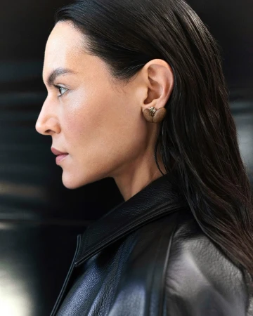 Profile portrait of a woman wearing a black leather jacket and a heart-shaped earring in London by Theresa Marx.