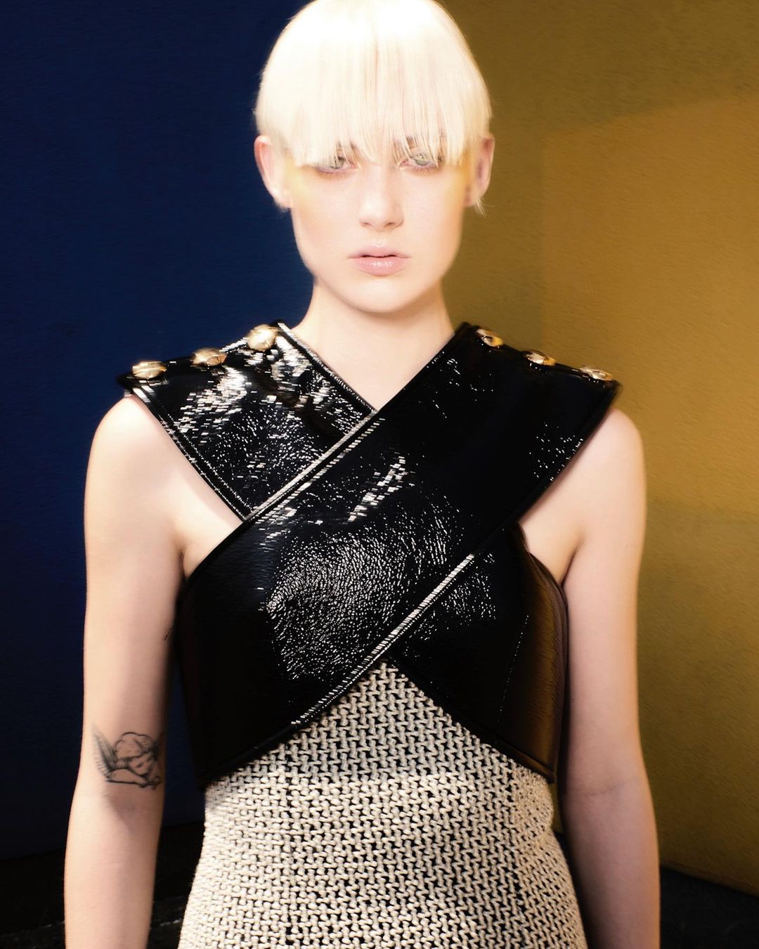 Model with platinum blonde hair wearing a black patent leather cross-strap top photographed by Theresa Marx.