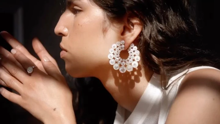 Elegant portrait of a woman showcasing large, round diamond earrings and a matching ring in soft, natural light, emphasizing beauty and jewelry.