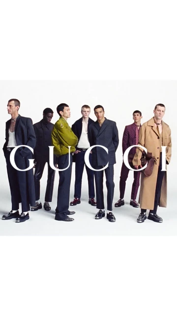 Gucci fashion campaign featuring a group of seven adult men posing in modern suits, jackets, pants, and coats against a stark white backdrop.