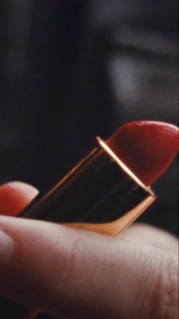 Close-up of a hand holding an open red lipstick in a gold case photographed by Thibault Della Gaspera in Paris