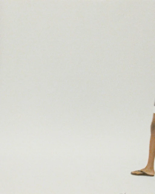 Partial view of an adult with dark hair, wearing shorts and flip-flops, stands against a plain white background, creating a minimalistic fashion shot.