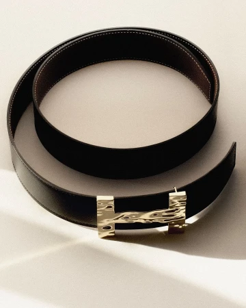 Elegant brown leather belt with a gold-toned textured H-shaped buckle, perfectly styled on a neutral surface. Fashion accessory.