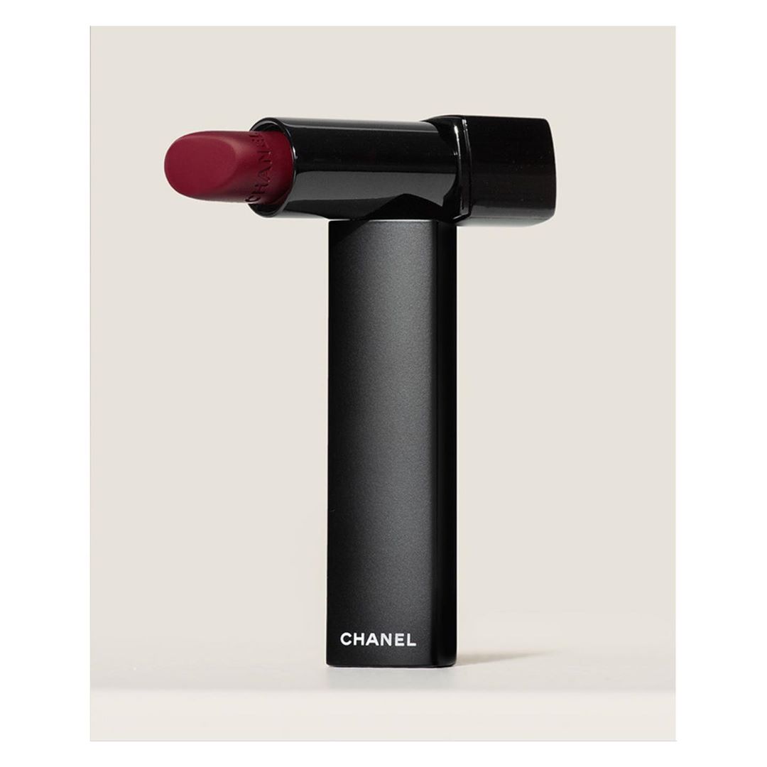 Still life studio shot of an opened matte black lipstick tube by Chanel with the lipstick bullet exposed on a white background.