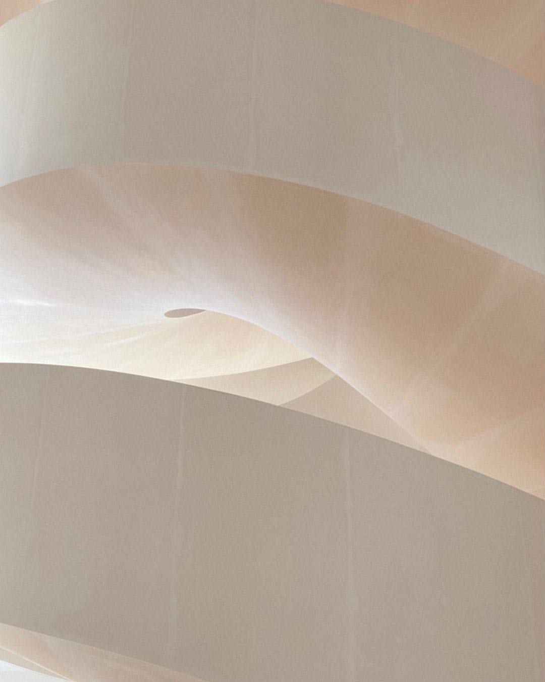 Abstract view of curved architectural details, showcasing smooth plaster walls in pale beige and white tones with natural light casting soft shadows.