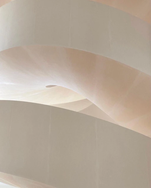 Abstract view of curved architectural details, showcasing smooth plaster walls in pale beige and white tones with natural light casting soft shadows.