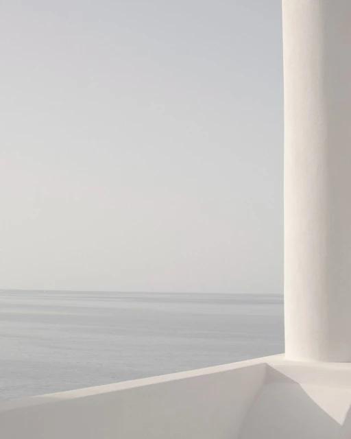 Minimalist view of the sea and sky from a white terrace with a rounded architectural column, creating a serene and clean aesthetic.